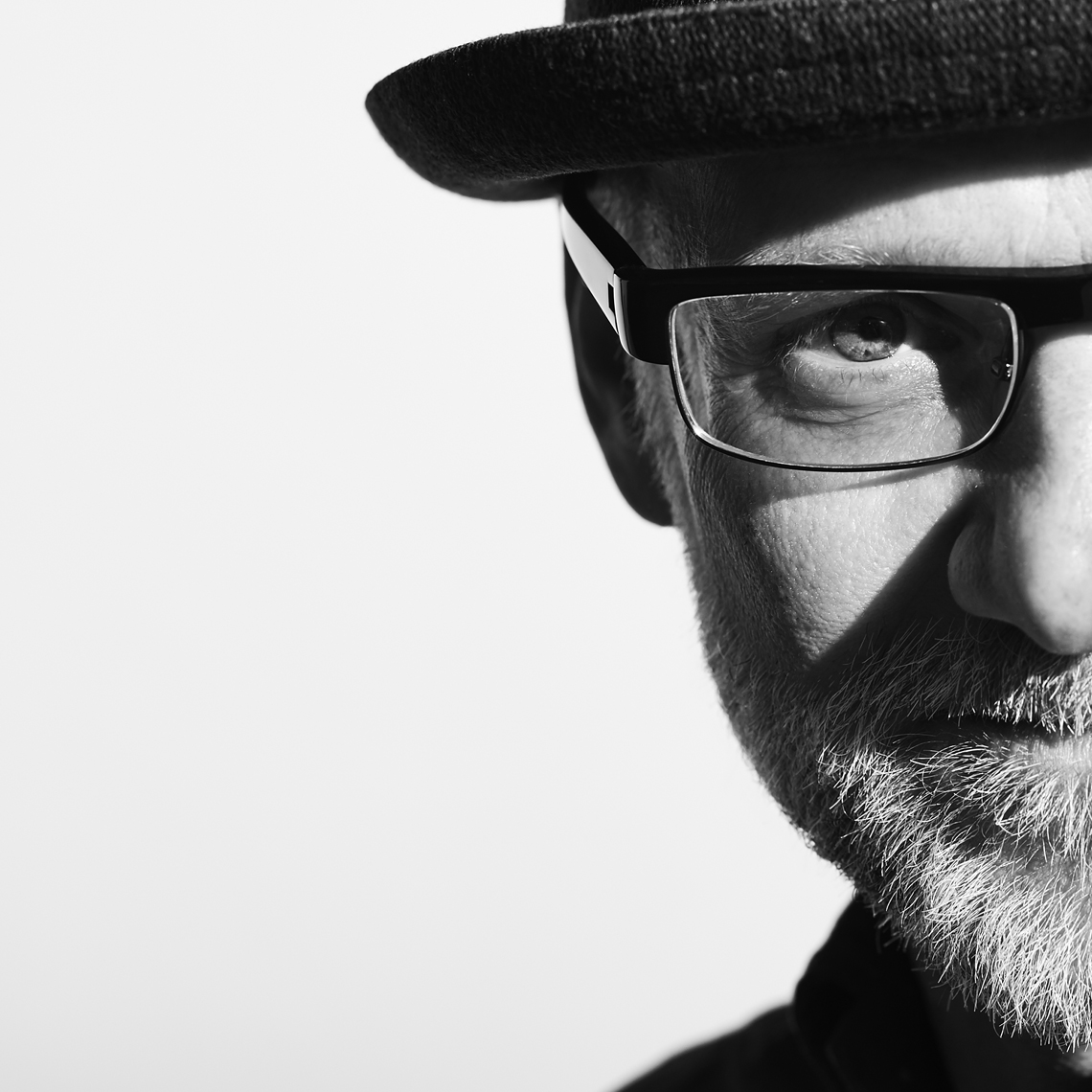Black and white portrait of white man in a hat with beard and glasses
