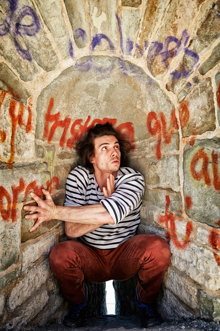 Young French man crouched in a small space with graffitti
