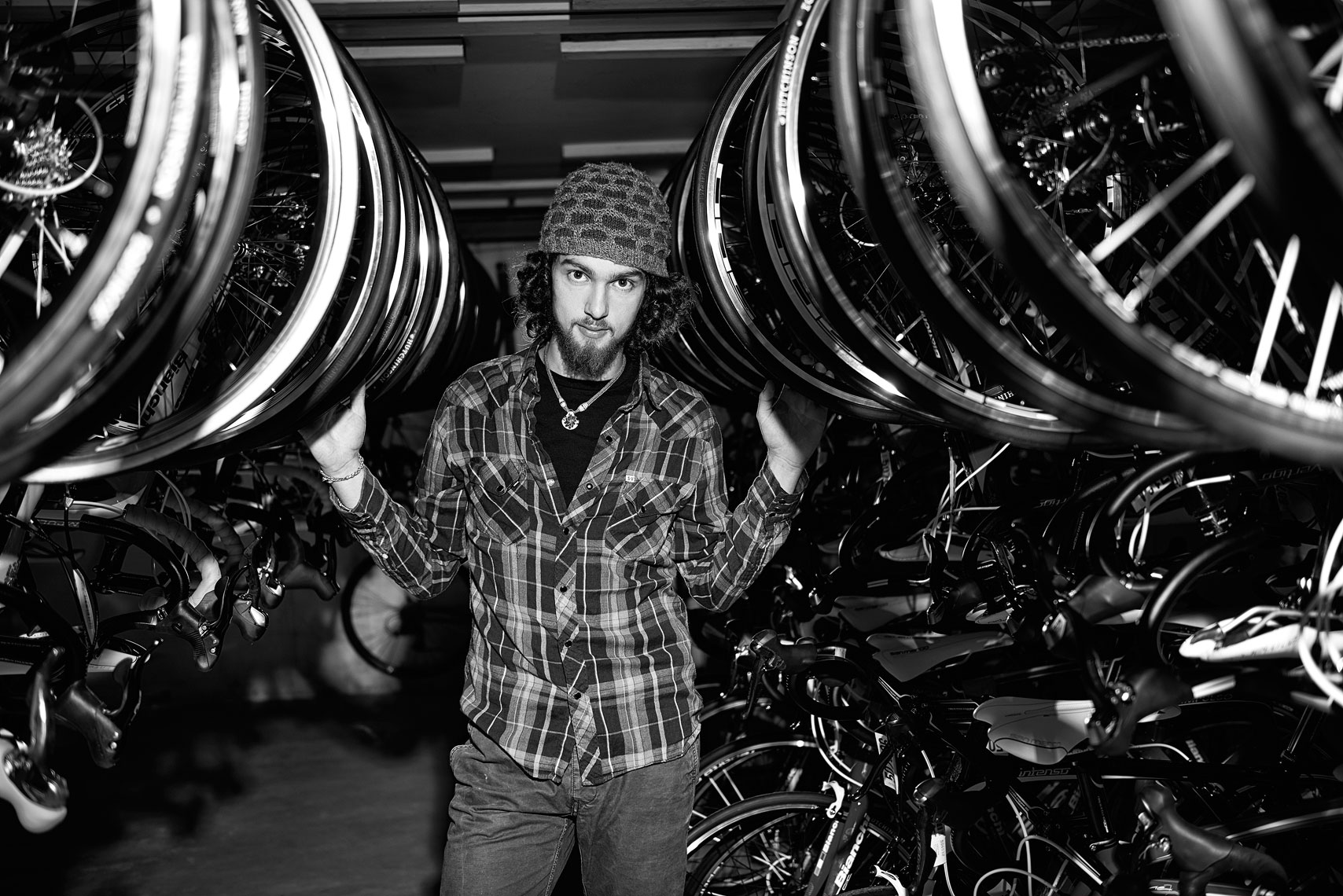 Black and white of a young man in a bike shop millennial beard